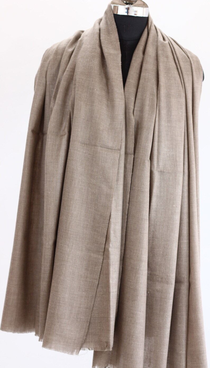 May include: A brown pashmina shawl draped over a mannequin. The shawl is made of a soft, lightweight fabric and has a subtle sheen.