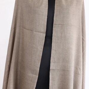 May include: A light brown pashmina shawl made of soft wool. The shawl is draped over a mannequin and has a simple, elegant design.