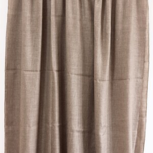 May include: A brown woven shawl hanging on a wooden rod. The shawl is made of a soft, lightweight fabric and has a subtle sheen.