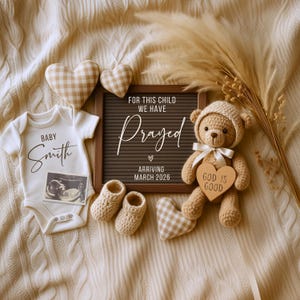 Puede incluir: Una conmovedora composición con un body de bebé con el nombre "Smith", una pizarra con el texto "For this child we have prayed, arriving March 2026", y un osito de peluche sosteniendo un letrero en forma de corazón que dice "God is Good".