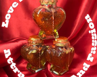 Könnte beinhalten: Drei herzförmige Glasbehälter, gefüllt mit einer goldenen Flüssigkeit, gestapelt auf einem roten Satinhintergrund. Die Behälter haben Korken und eine rot-orangefarbene Substanz, die an den Seiten heruntertropft. Text in Weiß um die Behälter: "Love Honey Jar" und "Attract Love And Passion."