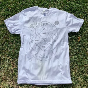 May include: White t-shirt with a black geometric design featuring circles, triangles, and the numbers 369, 666, 777, and 8888.