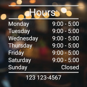 May include: A sign with the hours of operation for a business. The sign is on a blurry background with lights. The hours are: Monday - Friday 9:00 AM to 5:00 PM, Saturday 9:00 AM to 5:00 PM, and Sunday Closed. The phone number is 123 123-4567.