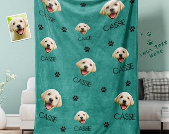 May include: A teal fleece blanket with a repeating pattern of a dog's face and paw prints. The dog's name "Cassie" is printed on the blanket.