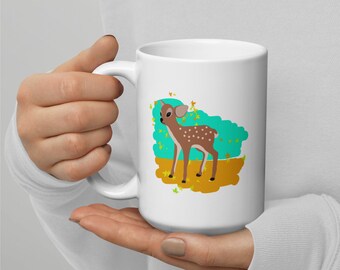 May include: White ceramic mug with a brown and white deer illustration on a turquoise and yellow background. The deer is standing in a field of yellow leaves.