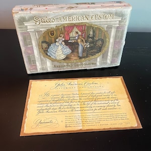 May include: A vintage box of Gales American Custom Assorted Chocolates with a guarantee card. The box features a hand-painted illustration of a couple in a parlor setting. The guarantee card states that the chocolates are packed in perfect condition and can be returned to any Rexall Drug Store for a cash refund or exchange.