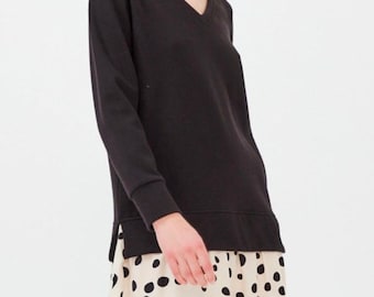 May include: A black long-sleeved v-neck sweater with a white and black polka dot skirt.