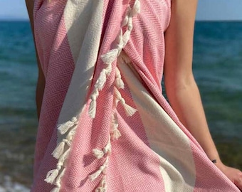 May include: A pink and white striped towel with white fringe tassels. The towel is made of cotton and is soft and absorbent. It is perfect for use at the beach or pool.