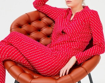 May include: A woman wearing a red and white polka dot pajama set, sitting in a brown leather chair.