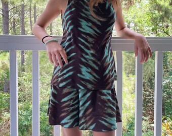 Könnte beinhalten: Ein braunes und türkisfarbenes ärmelloses Kleid mit einem Batik-Muster. Das Kleid hat einen Rüschen-Saum und ist aus einem weichen, bequemen Stoff gefertigt.