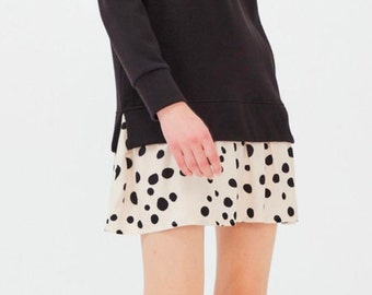 May include: A black long-sleeved v-neck sweater with a white and black polka dot skirt.