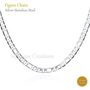 May include: Silver stainless steel Figaro chain. The chain has a repeating pattern of elongated and oval links. The text "Figaro Chain" and "Silver Stainless Steel" are in the upper left corner.