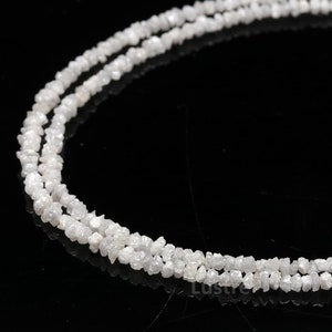 May include: A strand of white rough diamonds strung together as a necklace. The diamonds are irregular in shape and have a natural, unpolished look.