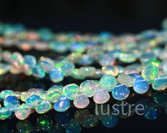 May include: A strand of iridescent opal beads in various shades of blue, green, and white. The beads are round and have a smooth, polished finish.