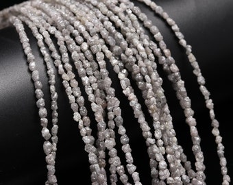 May include: A strand of rough, gray diamond beads. The beads are irregular in shape and have a natural, unpolished look.