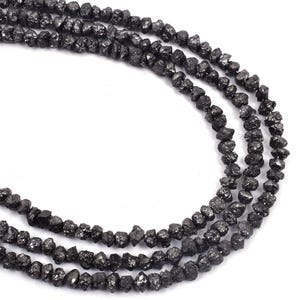 May include: A strand of black diamond beads. The beads are rough and unpolished, giving them a natural, earthy look.