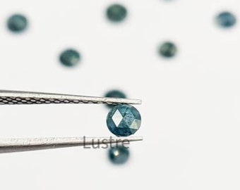 May include: A small, faceted, teal-colored gemstone is held by tweezers against a white background. The word "Lustre" is printed at the bottom. Several other gemstones are scattered in the background.