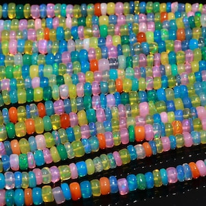 May include: A strand of colorful opal beads, featuring a mix of blue, green, yellow, pink, and orange hues. The beads are all approximately the same size and shape, and they are strung together on a clear thread.