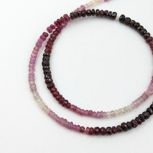 May include: A strand of pink, red, and purple gemstone beads. The beads are faceted and have a graduated colour effect.