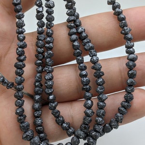 May include: A strand of black diamond beads, each bead is faceted and has a rough, natural texture. The beads are strung on a thin wire and are approximately 3mm in diameter.