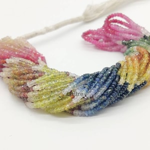 Peut inclure: Un fil de perles de pierres précieuses multicolores. Les perles passent du rose au jaune, vert et bleu. Les perles sont enfilées sur un cordon blanc, créant un affichage vibrant. Les pierres précieuses sont facettées.