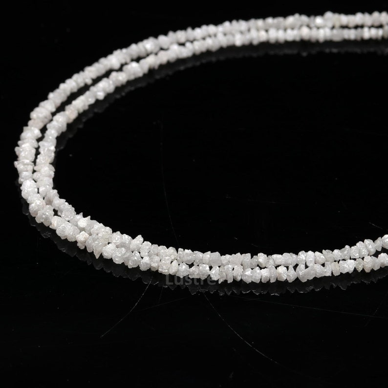 May include: A strand of white rough diamonds strung together as a necklace. The diamonds are irregular in shape and have a natural, unpolished look.
