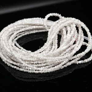 May include: A strand of white rough diamonds, also known as uncut diamonds, strung together on a white thread. The diamonds are small and have a natural, unpolished look.