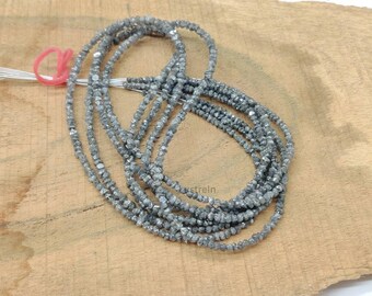 May include: A strand of gray diamond beads, approximately 16 inches long, on a wooden surface.