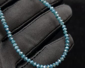May include: A strand of blue gemstone beads, likely diamonds, strung together on a thin cord. The beads are faceted and have a light blue color.