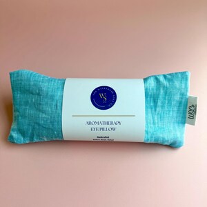 May include: A teal blue aromatherapy eye pillow with a white label that reads "The Weekend Soul Co." and "Aromatherapy Eye Pillow" with the text "Handcrafted" below.