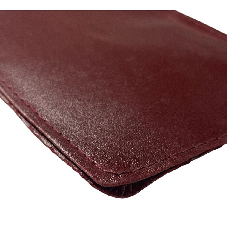 May include: Close-up view of a burgundy leather wallet. The wallet's surface is smooth with a subtle texture.  Stitching is visible along the edges. The leather appears soft and supple. The color is a deep, rich burgundy. The wallet is shown at an angle, highlighting its shape and texture. This is a high-quality leather wallet, suitable for everyday use.