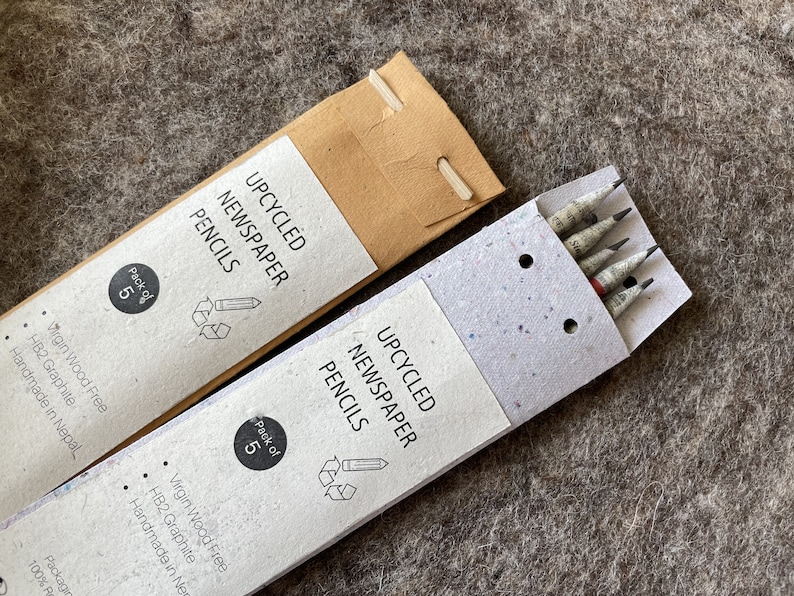 May include: Two packs of upcycled newspaper pencils. Each pack contains five pencils. The packaging is made of recycled paper. The pencils are HB2 graphite and handmade in Nepal.