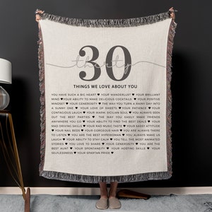 May include: A beige woven throw blanket with a gray number "30" and the text "Things We Love About You" followed by a list of positive attributes.