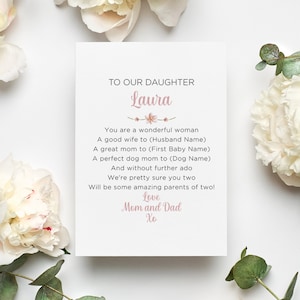 May include: A white card with a black background and text that reads "TO OUR DAUGHTER Laura". The card is surrounded by white flowers. The text includes a message to the daughter from her parents.