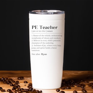 May include: A white cylindrical tumbler with a clear lid featuring black printed text that defines a PE Teacher as a master of the whistle, believer in every child's potential, and architect of joy, with the additional text See also: Ryan.