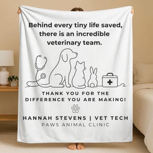 May include: A white fleece blanket featuring black line art of a stethoscope, a dog, a cat, a rabbit, and a medical kit. Text reads: Behind every tiny life saved, there is an incredible veterinary team. THANK YOU FOR THE DIFFERENCE YOU ARE MAKING! HANNAH STEVENS | VET TECH PAWS ANIMAL CLINIC.