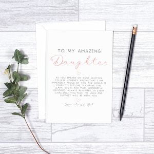 Pu&ograve; includere: Un biglietto bianco con testo rosa che dice "To my amazing Daughter". Il biglietto contiene un messaggio su quanto si &egrave; orgogliosi di una figlia che va al college e le augura buona fortuna nel suo percorso. Il biglietto &egrave; firmato "Love always, Dad".