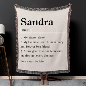 May include: Cream-colored throw blanket with the name "Sandra" in large black letters. The blanket includes a definition, and three descriptive phrases. The phrase "Love always, Danielle" is also printed on the blanket.