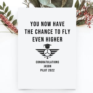 May include: A black and white graduation card with the text "You now have the chance to fly even higher. Congratulations Jason Pilot 2022". The card features a graduation cap with wings and a propeller.
