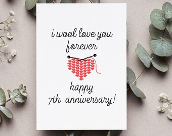May include: A white card with the text "i wool love you forever" and a red knitted heart with knitting needles. The card also says "happy 7th anniversary!"