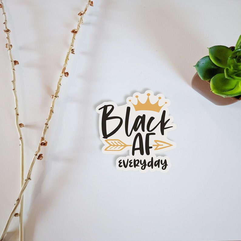May include: Black and gold sticker with the text "Black AF everyday" and a crown above the word "Black".
