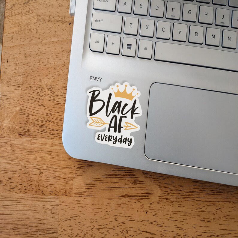 May include: A black and gold sticker with the text "Black AF Everyday" and a gold crown above the word "Black". An arrow points to the right.