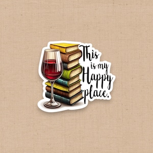 May include: A die-cut sticker featuring a stack of five colorful books next to a glass of red wine. The text "This is my Happy place." is written in black script to the right of the books. The illustration uses vibrant colors.