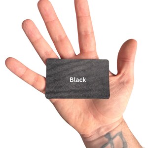 Puede incluir: Una tarjeta rectangular con una superficie texturizada de color gris oscuro que presenta la palabra Black impresa en blanco en el centro. La tarjeta tiene esquinas redondeadas y un acabado mate, ofreciendo un dise&ntilde;o simple para etiquetado.