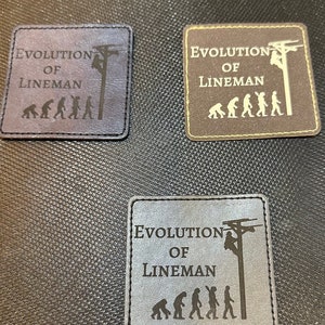 May include: Three brown leather patches with the text "Evolution of Lineman" and a silhouette of a lineman climbing a utility pole. The patches feature a series of stick figures representing the evolution of humans, ending with the lineman.