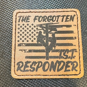 May include: A brown leather patch with a black silhouette of two linemen working on a power pole. The patch features a distressed American flag design and the text "THE FORGOTTEN 1ST RESPONDER".