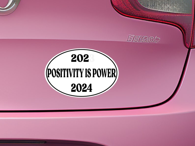 May include: White oval sticker with black text that reads "2023 POSITIVITY IS POWER 2024" on a pink car.