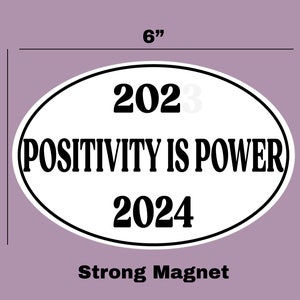 May include: White oval-shaped magnet with black text that reads "2023 POSITIVITY IS POWER 2024". The magnet is 6 inches wide and 4 inches tall. Strong Magnet.