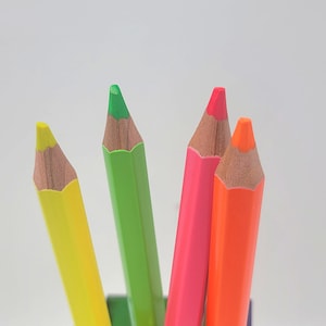 May include: Four sharpened colored pencils, one yellow, one green, one pink, and one orange.