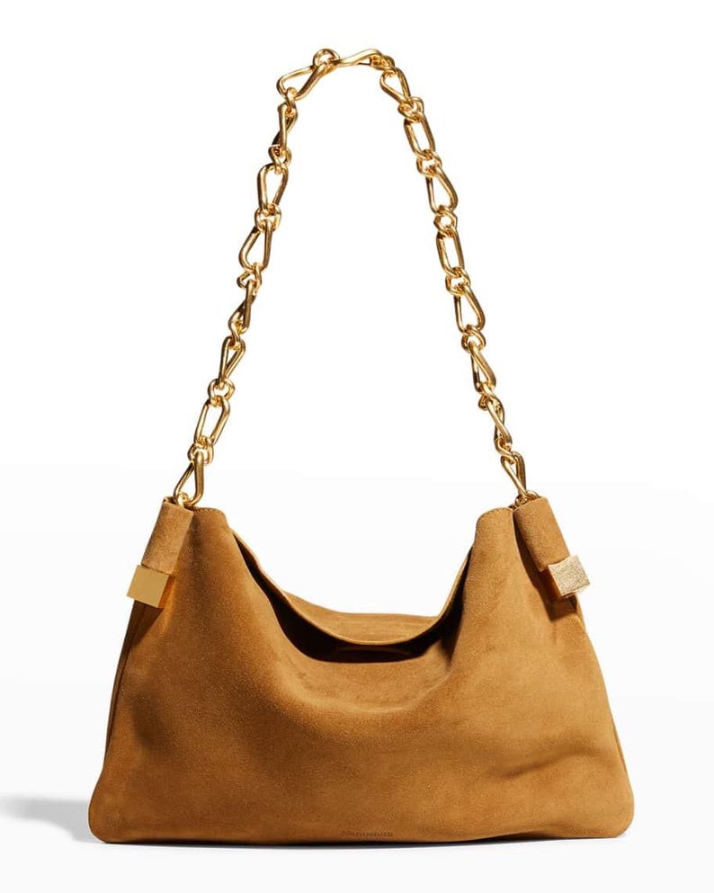 Może przedstawiać: Brązowa zamszowa torba na ramię ze złotym łańcuszkiem. Torba ma luźny design i złote akcenty w miejscu mocowania paska. Łańcuch składa się z dużych, zazębiających się ogniw.